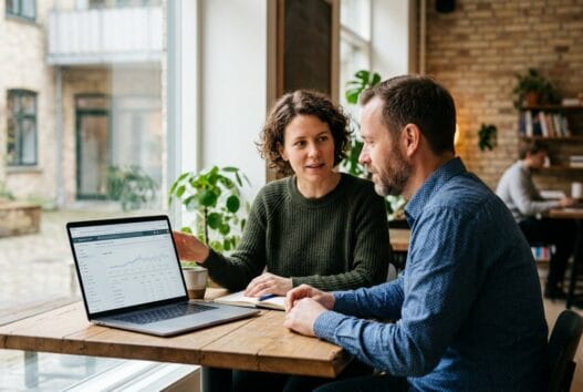 Freelancer rådgiver kunde om SEO ved et bord i et naturligt kontormiljø